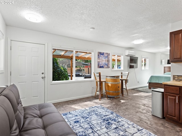 living room with a wall unit AC, baseboards, and a textured ceiling