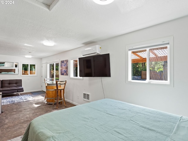 bedroom featuring a textured ceiling, hardwood / wood-style flooring, a wall unit AC, and multiple windows