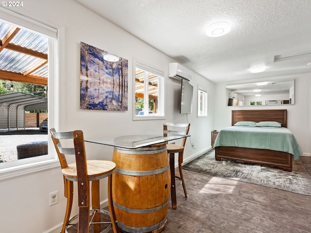 bedroom with a textured ceiling, a wall mounted AC, and hardwood / wood-style floors