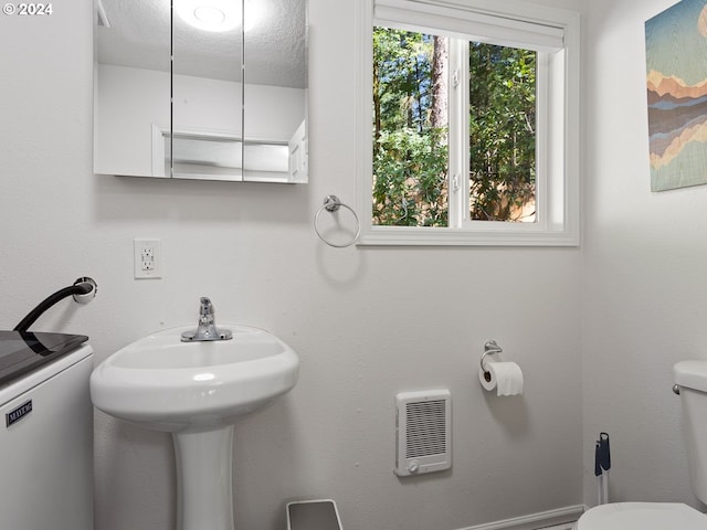 bathroom featuring toilet, plenty of natural light, sink, and a textured ceiling