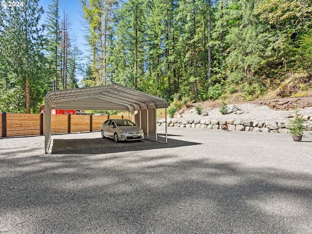 view of vehicle parking with a carport, fence, and driveway