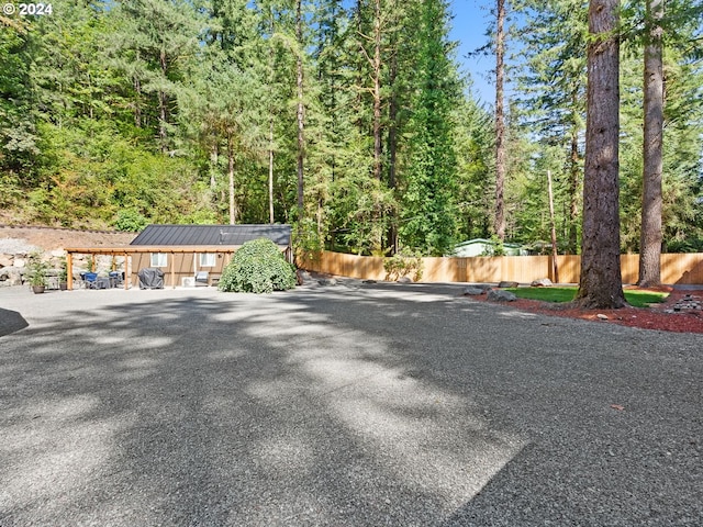 view of car parking featuring fence and a view of trees