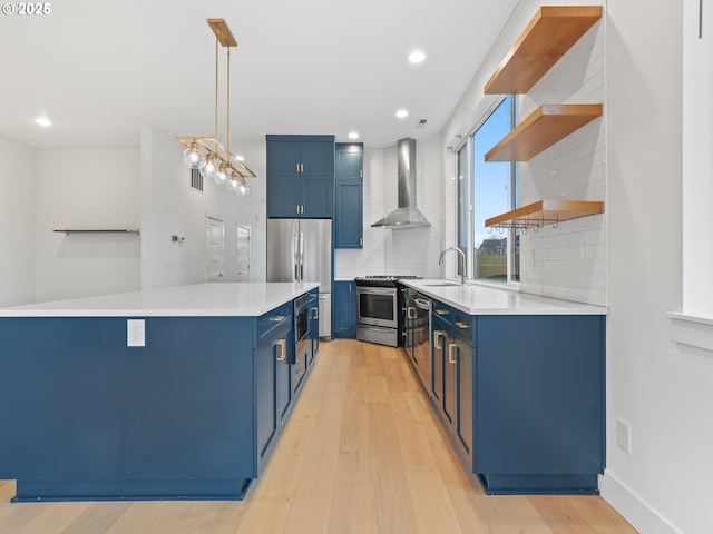 kitchen featuring blue cabinetry, open shelves, stainless steel appliances, backsplash, and wall chimney exhaust hood