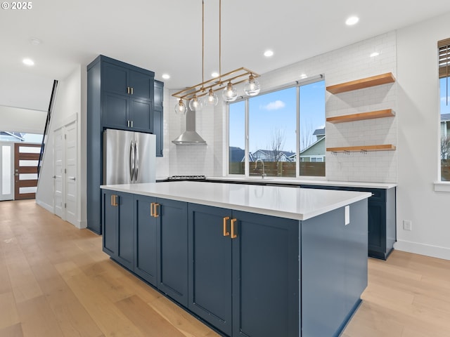 kitchen featuring light countertops, blue cabinetry, freestanding refrigerator, and tasteful backsplash