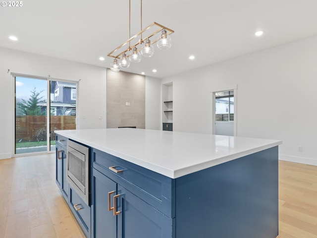 kitchen featuring stainless steel microwave, plenty of natural light, blue cabinetry, and light wood finished floors