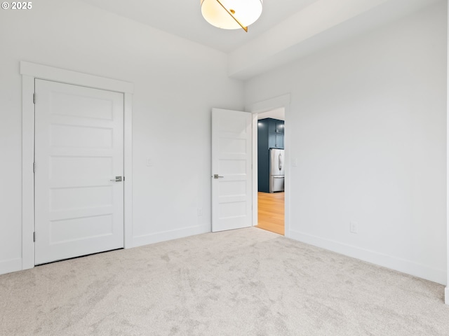 unfurnished bedroom featuring carpet, baseboards, and freestanding refrigerator