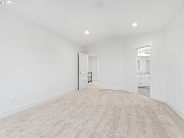 unfurnished bedroom with lofted ceiling, ensuite bathroom, recessed lighting, light colored carpet, and baseboards