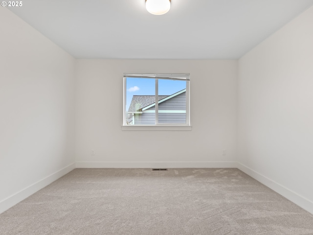 spare room featuring light colored carpet, visible vents, and baseboards