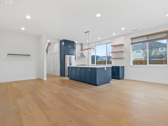 kitchen featuring stainless steel appliances, light countertops, decorative backsplash, light wood-style floors, and blue cabinets