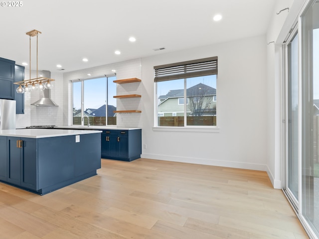 kitchen with blue cabinets, light countertops, backsplash, and light wood finished floors