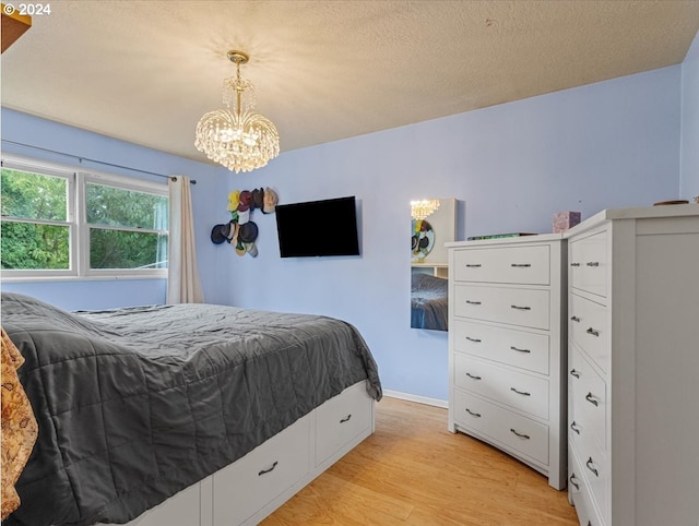 bedroom with an inviting chandelier, a textured ceiling, and light wood-type flooring