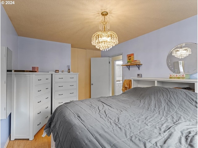 bedroom featuring light hardwood / wood-style floors, a textured ceiling, and a chandelier