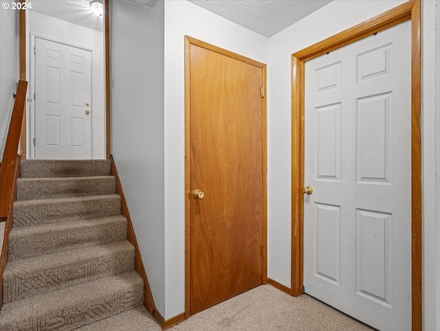 stairway with carpet and a textured ceiling