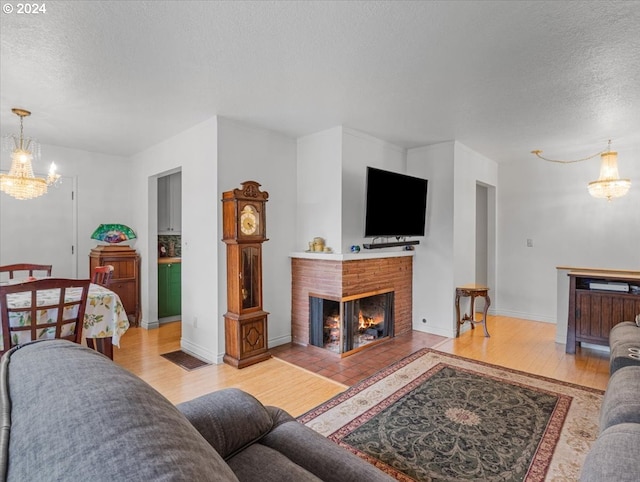 living room with a textured ceiling, light hardwood / wood-style flooring, a multi sided fireplace, and an inviting chandelier