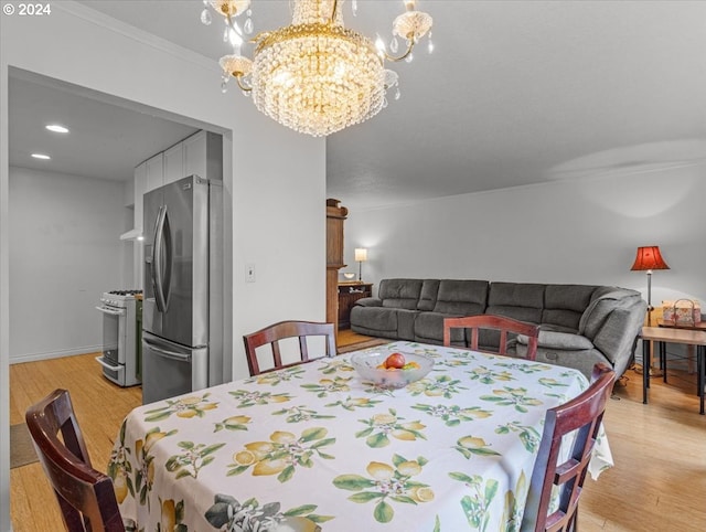 dining space with crown molding, light hardwood / wood-style flooring, and an inviting chandelier