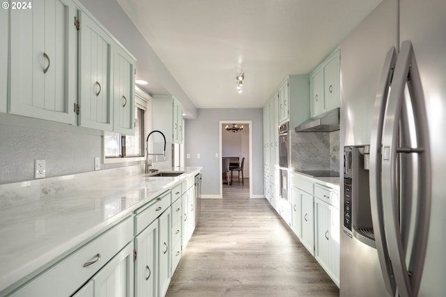 kitchen with sink, stainless steel appliances, ventilation hood, backsplash, and light hardwood / wood-style floors