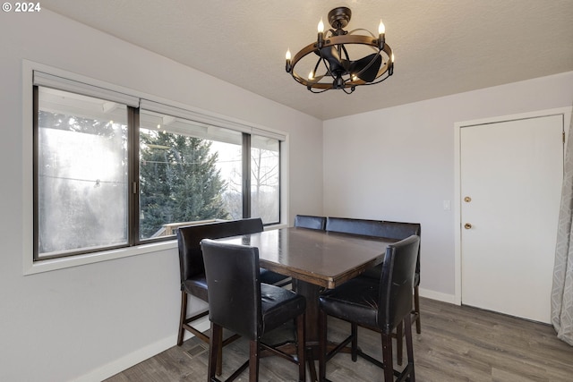 dining area featuring hardwood / wood-style floors, a textured ceiling, and an inviting chandelier