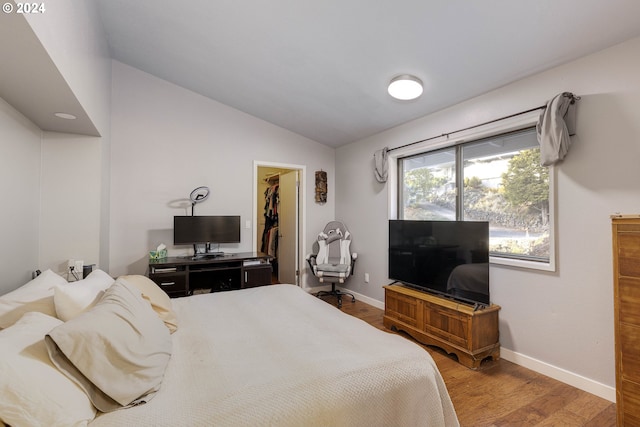 bedroom with hardwood / wood-style floors, a spacious closet, a closet, and lofted ceiling