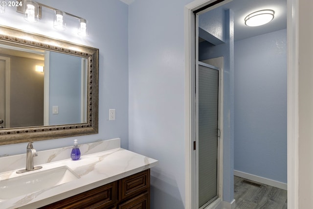 bathroom with hardwood / wood-style floors, vanity, and a shower with door