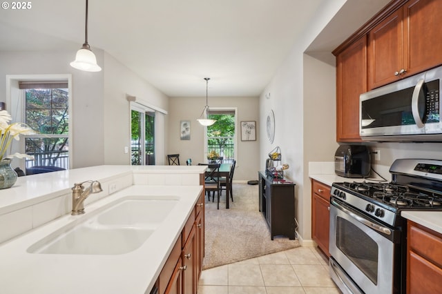 kitchen featuring light carpet, sink, stainless steel appliances, and decorative light fixtures