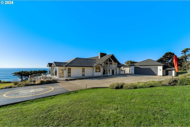 view of front of home with a front lawn, a water view, and a garage