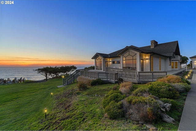 view of front facade featuring a lawn and a deck with water view