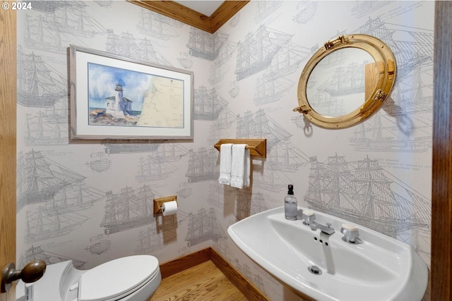 bathroom featuring hardwood / wood-style flooring, toilet, ornamental molding, and sink