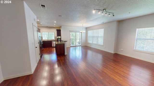 living room with a textured ceiling, a chandelier, and dark wood-type flooring