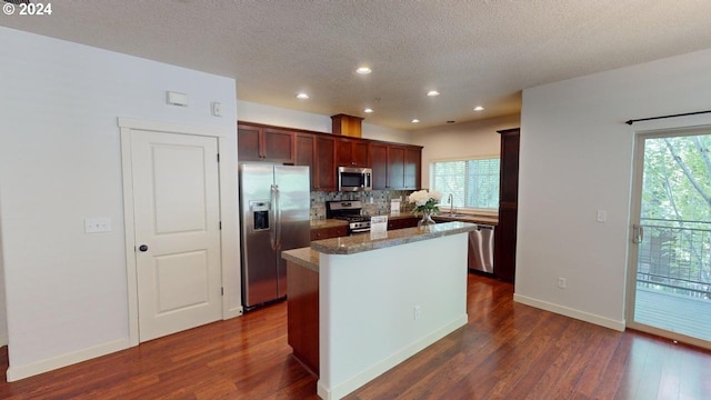 kitchen with a center island, stainless steel appliances, a healthy amount of sunlight, and dark hardwood / wood-style flooring