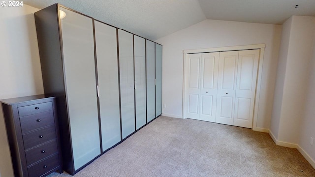 unfurnished bedroom with a closet, light colored carpet, and vaulted ceiling