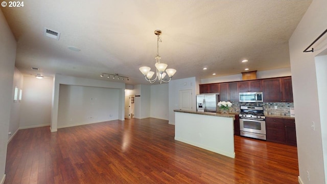 kitchen with tasteful backsplash, appliances with stainless steel finishes, dark wood-type flooring, a notable chandelier, and decorative light fixtures