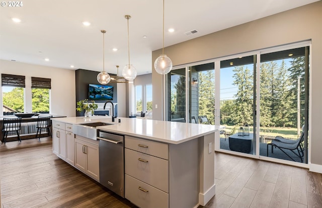 kitchen featuring pendant lighting, sink, stainless steel dishwasher, an island with sink, and white cabinetry