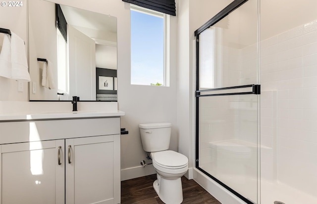 bathroom featuring hardwood / wood-style floors, vanity, toilet, and an enclosed shower