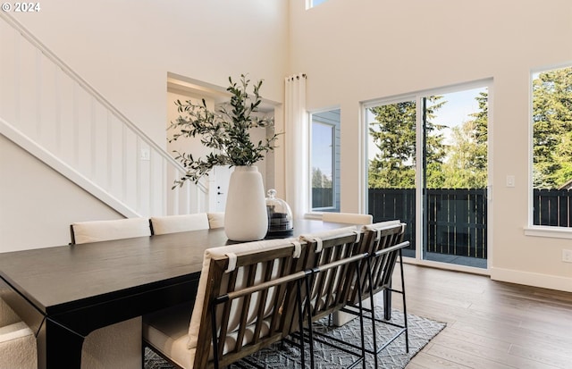 dining space featuring a towering ceiling and hardwood / wood-style flooring