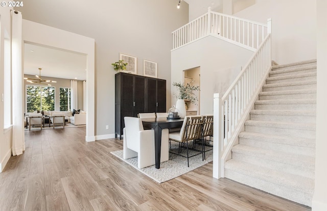 living room featuring ceiling fan, a high ceiling, and light hardwood / wood-style flooring