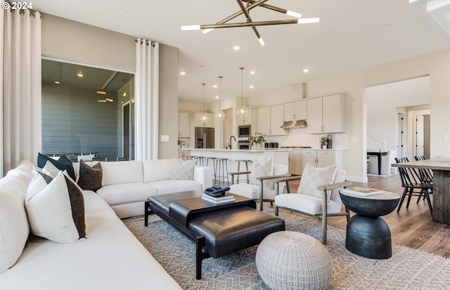 living room featuring light hardwood / wood-style flooring, an inviting chandelier, and sink