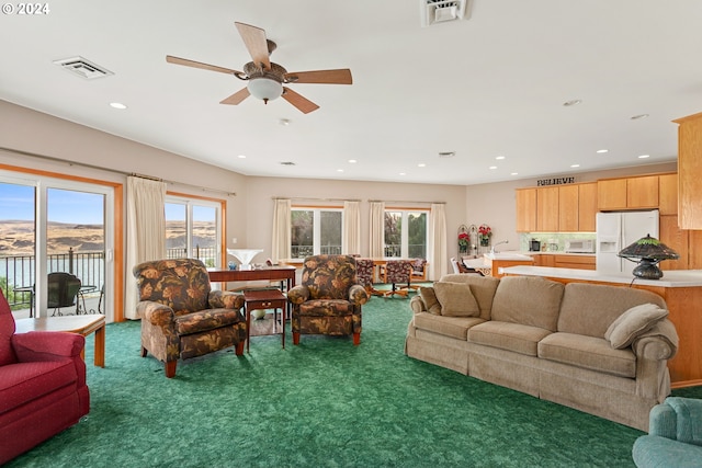 living room featuring ceiling fan and dark colored carpet