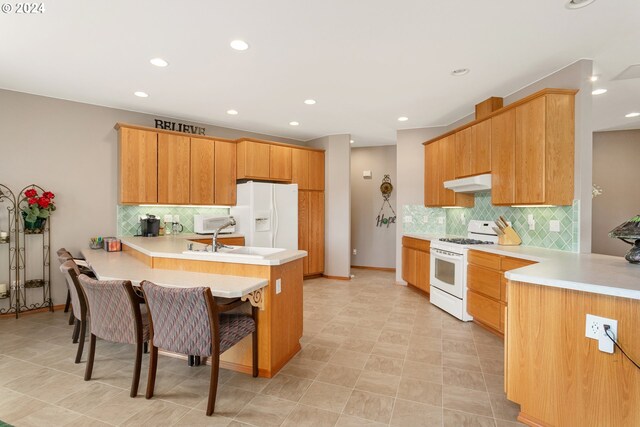 kitchen with backsplash, kitchen peninsula, white appliances, and a breakfast bar area