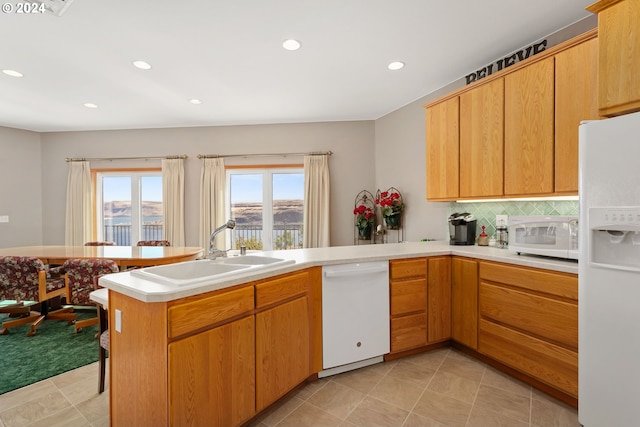 kitchen with white appliances, kitchen peninsula, sink, decorative backsplash, and light tile patterned flooring