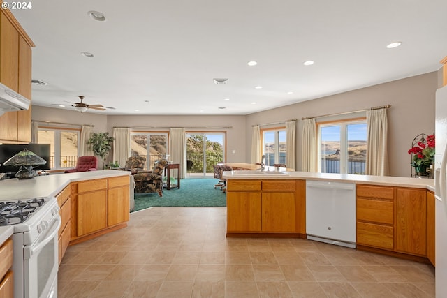 kitchen with white appliances, kitchen peninsula, and ceiling fan