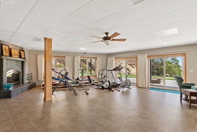 workout area featuring a wealth of natural light, a paneled ceiling, ceiling fan, and a fireplace