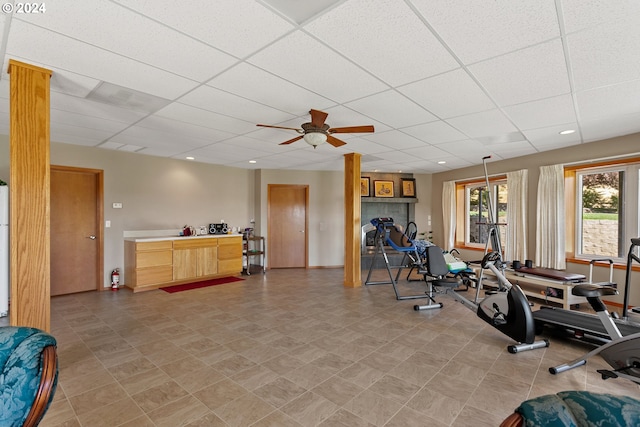 exercise area featuring ceiling fan and a drop ceiling