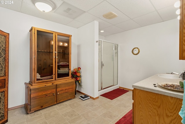 bathroom featuring tile patterned flooring, a shower with shower door, a paneled ceiling, and vanity