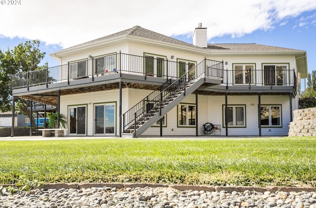 rear view of house featuring a wooden deck, a lawn, and a patio