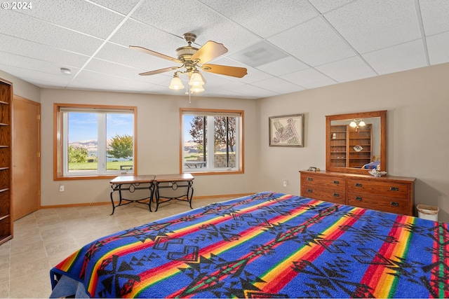 tiled bedroom with ceiling fan and a drop ceiling