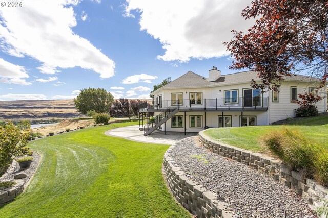 back of property with a balcony, a yard, and a patio