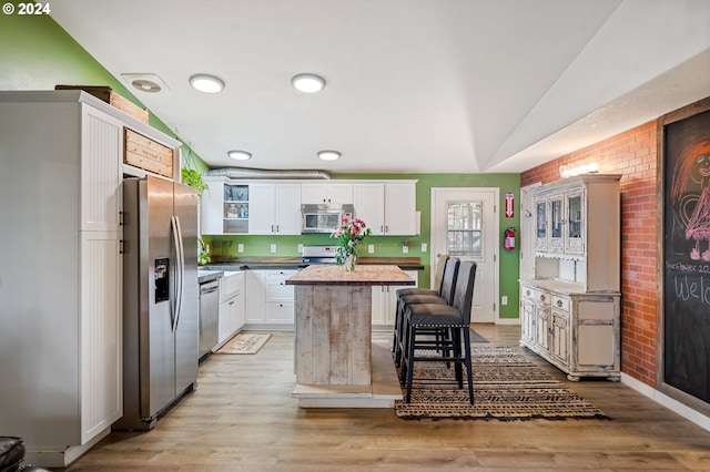 kitchen with light hardwood / wood-style floors, stainless steel appliances, butcher block countertops, white cabinetry, and lofted ceiling