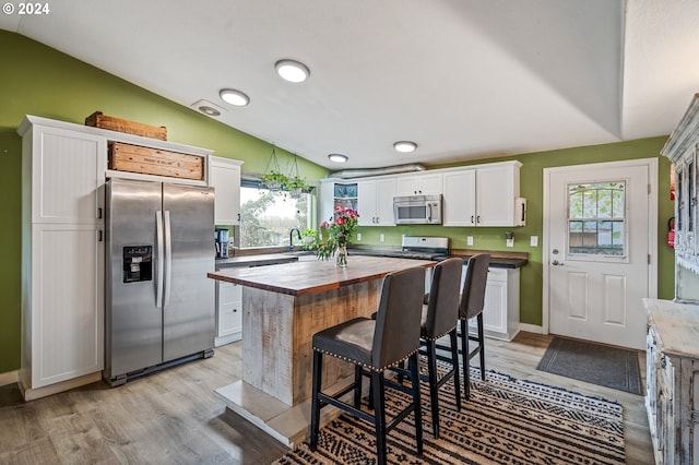 kitchen with wood counters, stainless steel appliances, light hardwood / wood-style floors, white cabinetry, and lofted ceiling