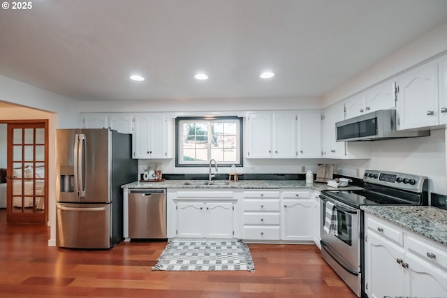 kitchen with white cabinetry, sink, light stone counters, and appliances with stainless steel finishes