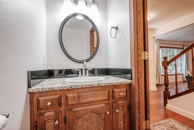 bathroom with vanity, wood-type flooring, and a textured ceiling